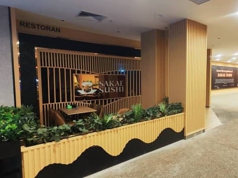 The Sakae Sushi restaurant frontage in a mall, with timber screens and planters.