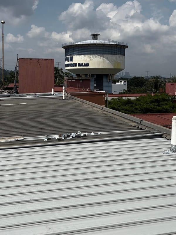 A metal roof with the Universiti Malaya water tower behind.