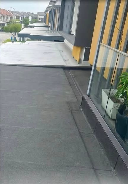 The terrace finished in dark membrane beside a glass balustrade, with potted plants.