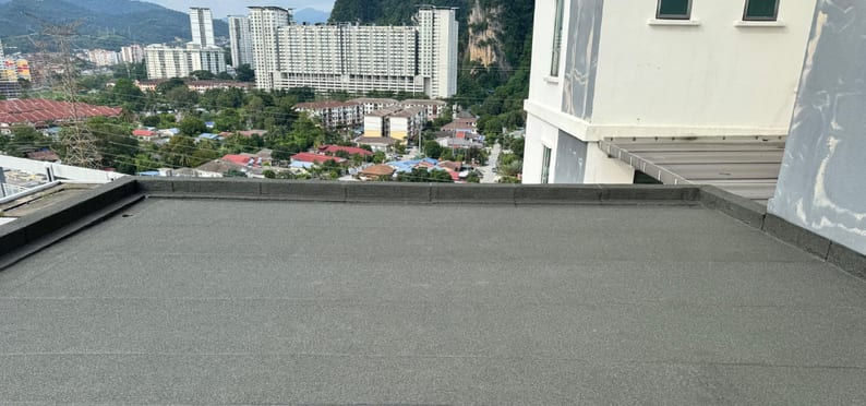 The rooftop slab finished in dark membrane, apartment blocks behind.
