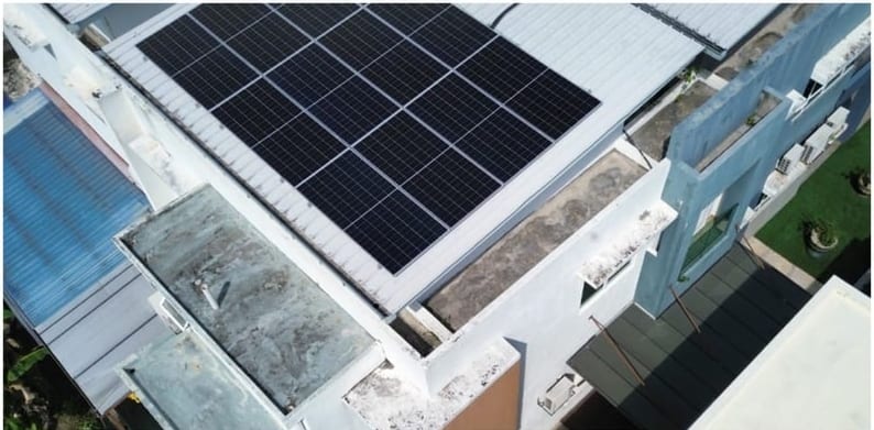 A worn flat roof section beside a solar array, seen from above.