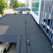 A lit gas torch heating a roll of membrane on a roof.